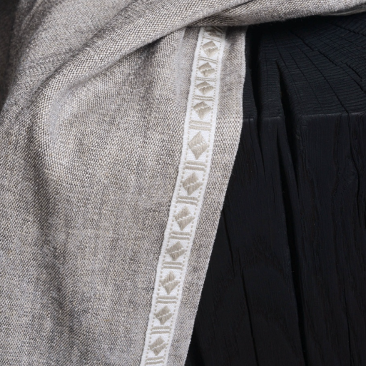 Close-up of a gray fabric with a decorative white border on a black background