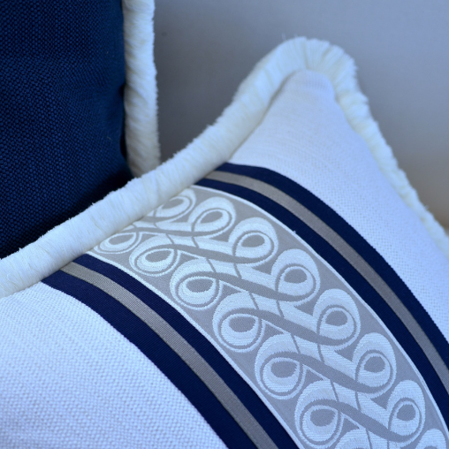 White pillow with blue decorative band on a neutral background