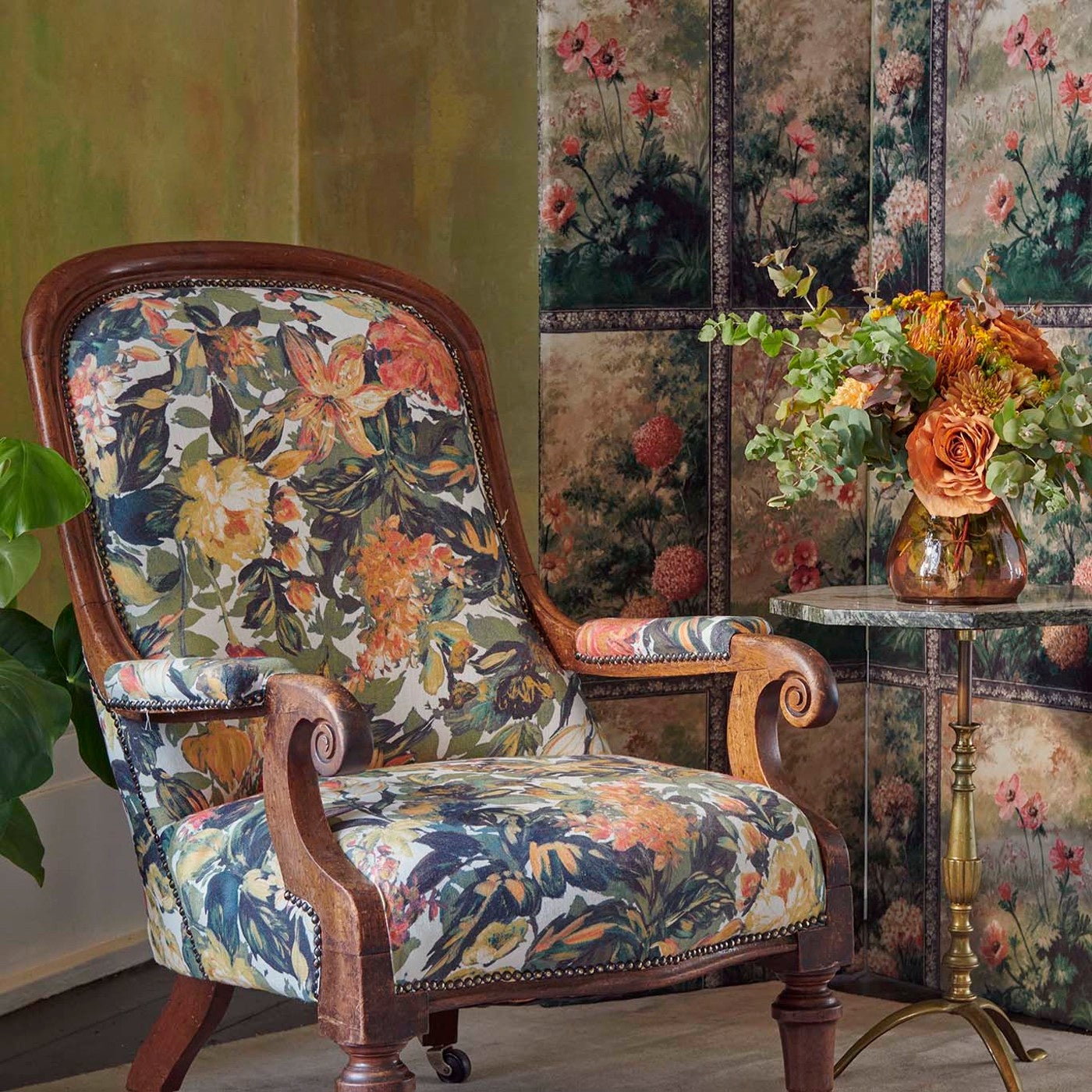 Elegant armchair upholstered in Botanical Blooms Olive/Raspberry fabric with a floral design, styled in a classic interior setting.