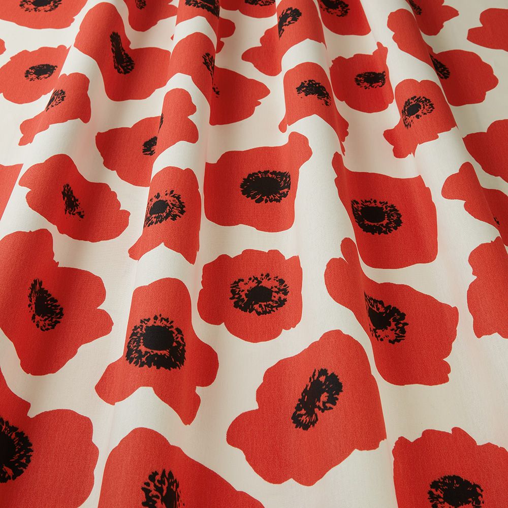 Close-up of Large Poppy Jet Red Scandi fabric with bold red poppy prints and black accents on a cream cotton textile, perfect for sewing projects.