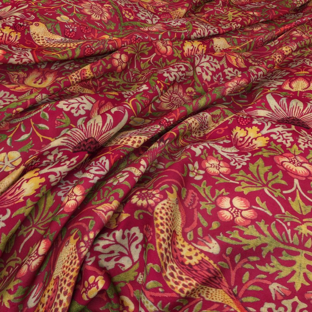 Close-up of William Morris Velvet Strawberry Thief Claret fabric with rich red, gold, and green floral and bird designs. Perfect for crafting and home decor.