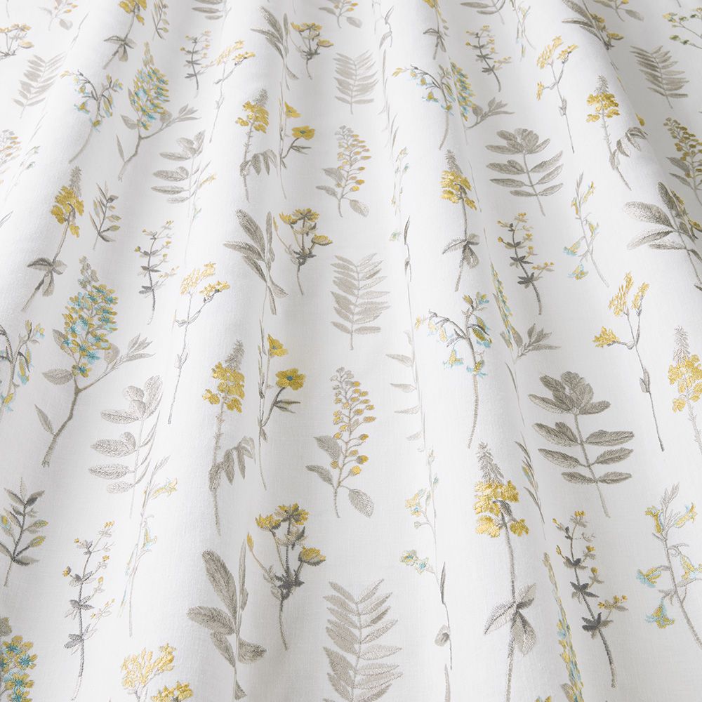 Close-up of Wild Flora Cornsilk fabric showcasing intricate floral patterns with yellow and green accents, perfect for home décor projects.