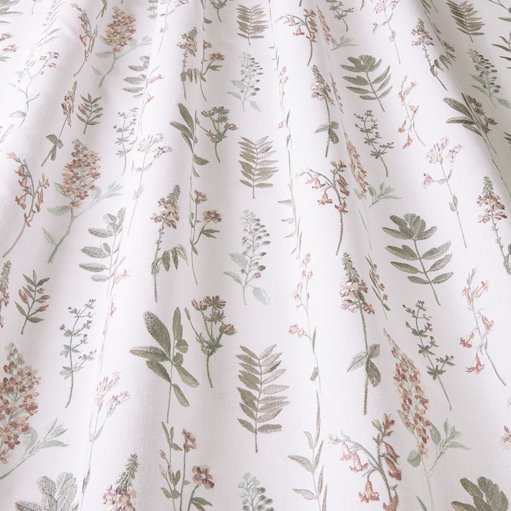Close-up of Wild Flora Orchid fabric displaying intricate floral embroidery with natural motifs in muted green and pink hues.