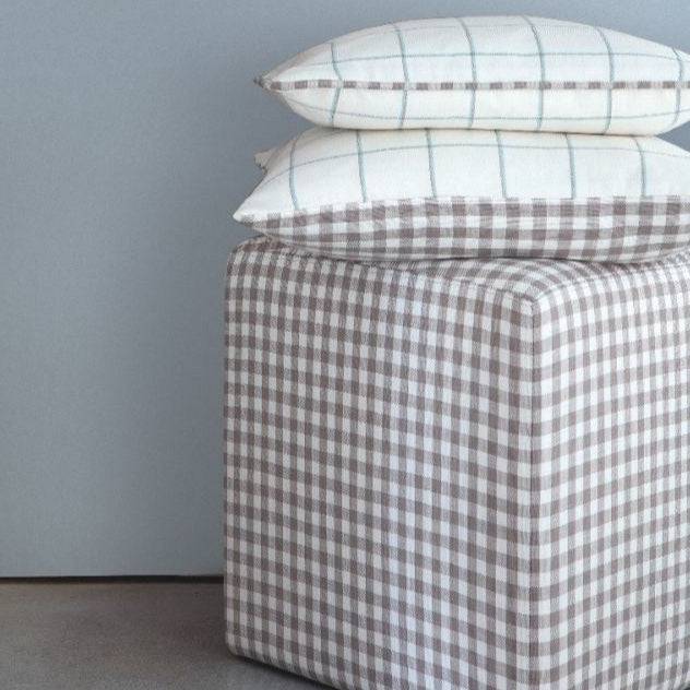 Beechwood Natural gingham check fabric used on a cube ottoman and pillows, showcasing its versatility for home décor.
