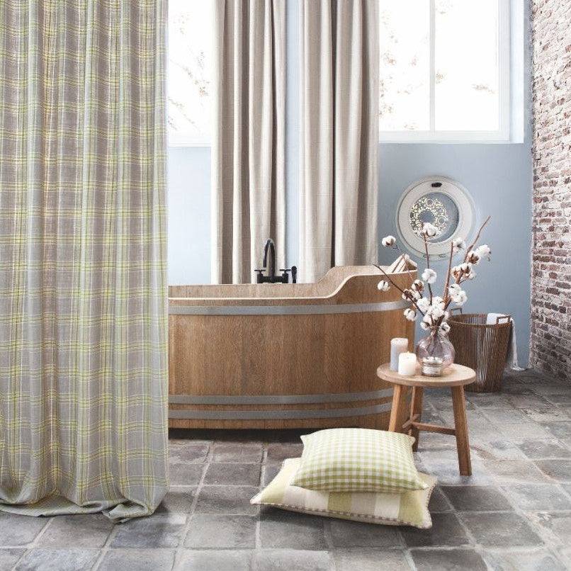 Bathroom décor with Beechwood Moss gingham fabric pillows, neutral linen curtains, and a wooden bathtub in a rustic setting.