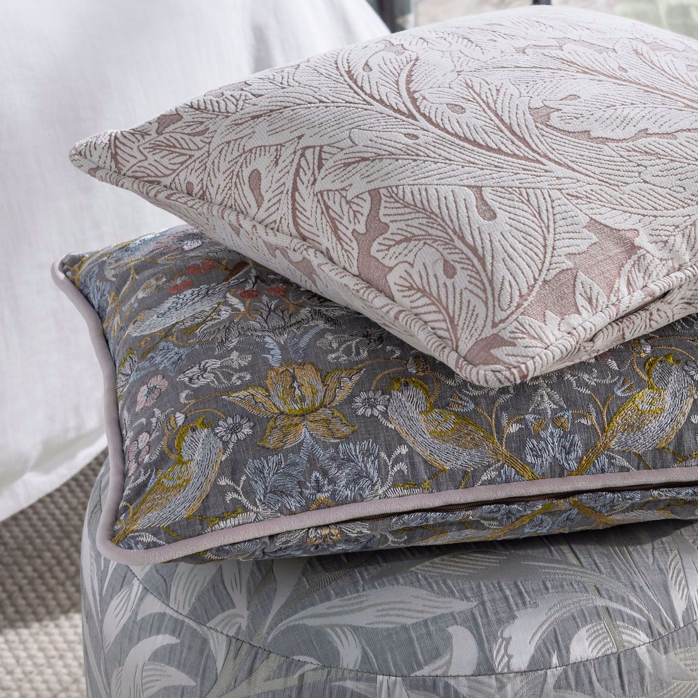 William Morris-inspired cushions with intricate floral and bird patterns.