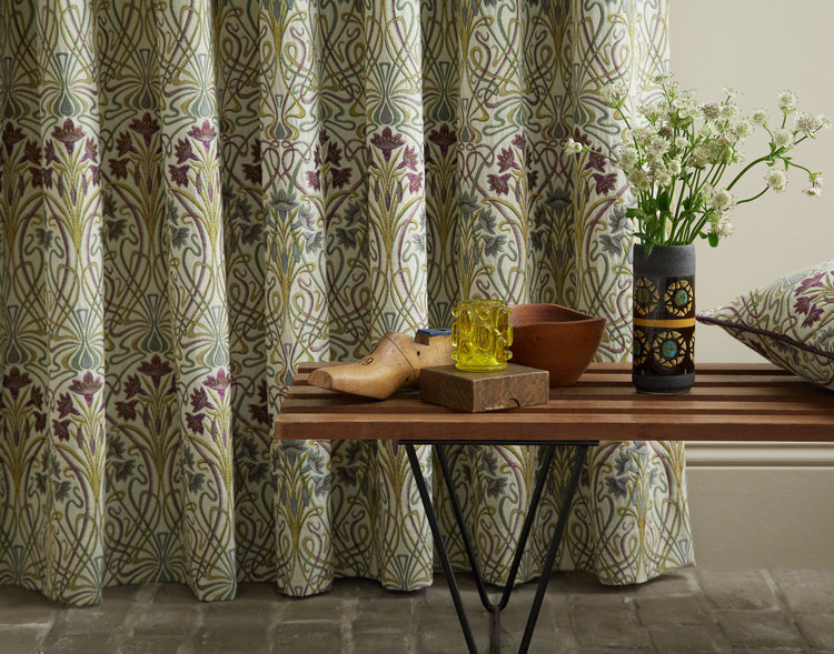 Art Nouveau-inspired décor with floral-patterned curtains, wooden bench, and vintage accents.