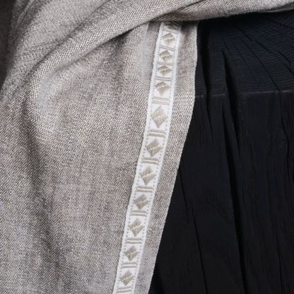 Close-up of a gray fabric with a decorative white border on a black background