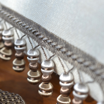 Close-up of decorative fabric trim with beads on a wooden surface