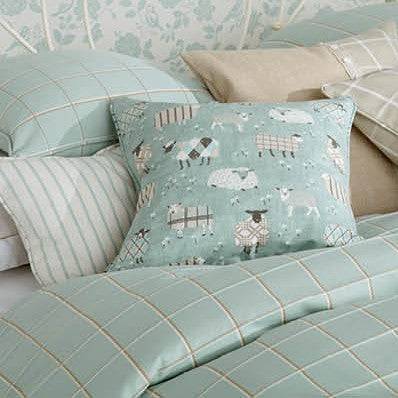 Decorative cushion and bedding made with Grazing Pastures Duck Egg sheep fabric, perfect for cosy and playful children's bedroom décor.
