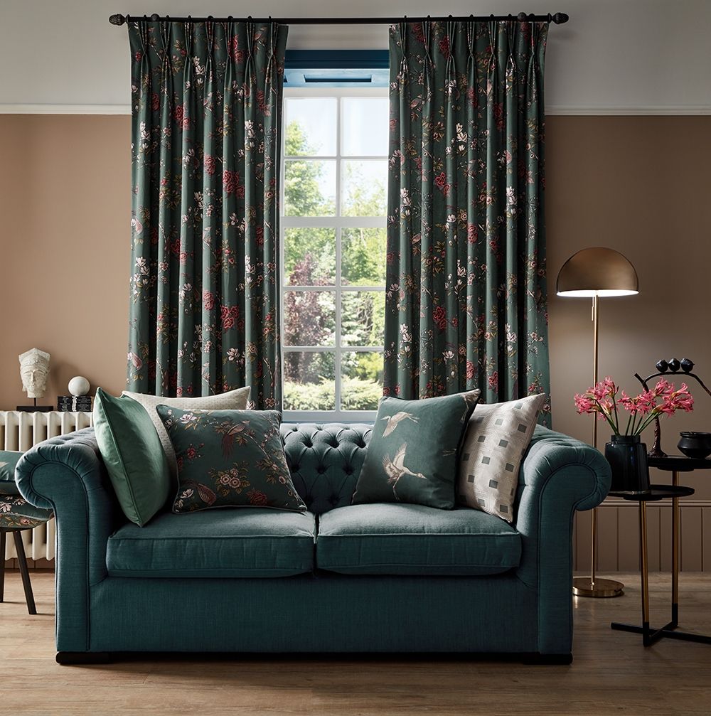 Living room with Sakura Kyoto Emerald curtains and cushions, complementing a green sofa in a cosy, elegant setting.