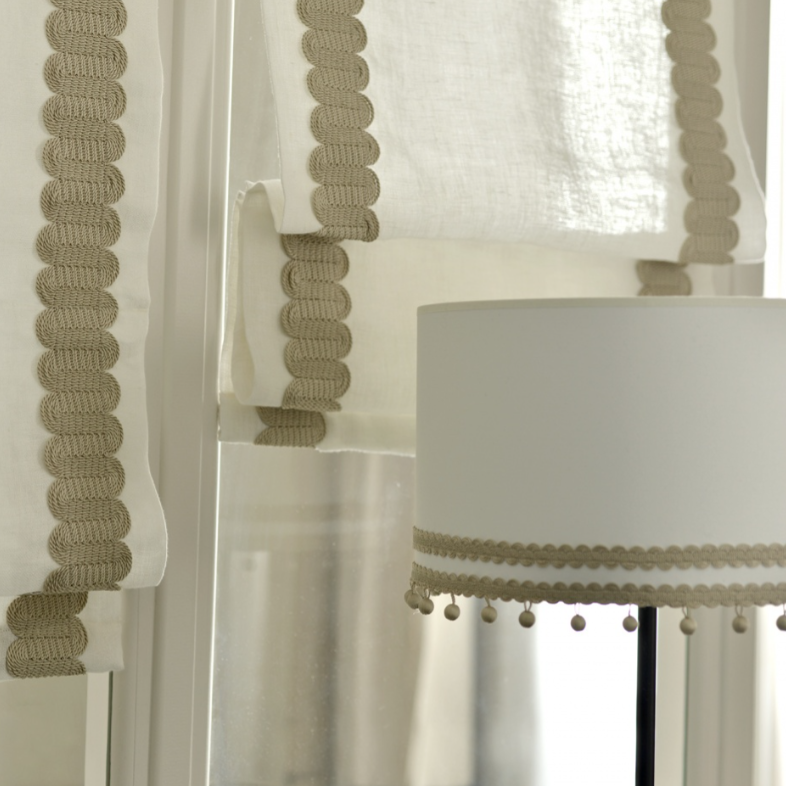 Close-up of a lamp with a decorative shade against a white curtain background