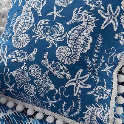 Close-up of Maris Navy sea life fabric on cushion, showcasing detailed white crabs, seahorses, and turtles on blue cotton for coastal-themed décor.