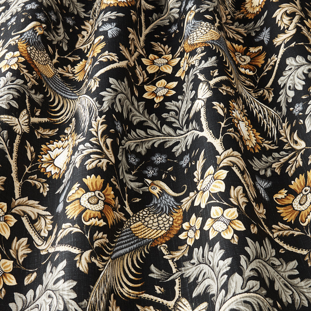 Close-up of Opus Floral Saffron cotton fabric showcasing detailed saffron and black floral and bird patterns, perfect for drapes and creative projects.