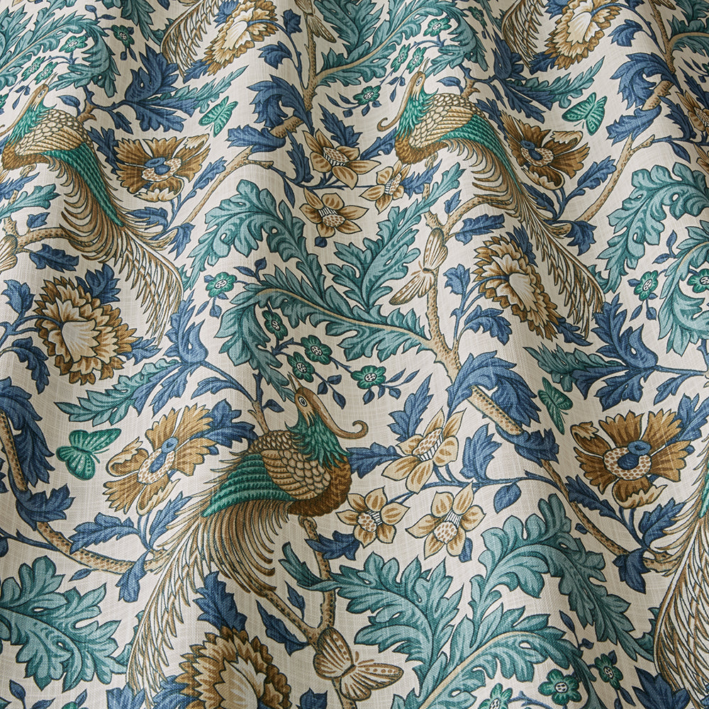 Close-up of Opus Floral Verdigris cotton fabric showcasing detailed peacock and floral motifs in vibrant blue, green, and gold hues for curtains or upholstery.