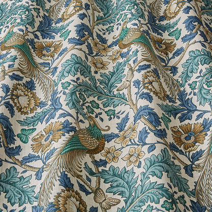 Close-up of Opus Floral Verdigris cotton fabric showcasing detailed peacock and floral motifs in vibrant blue, green, and gold hues for curtains or upholstery.