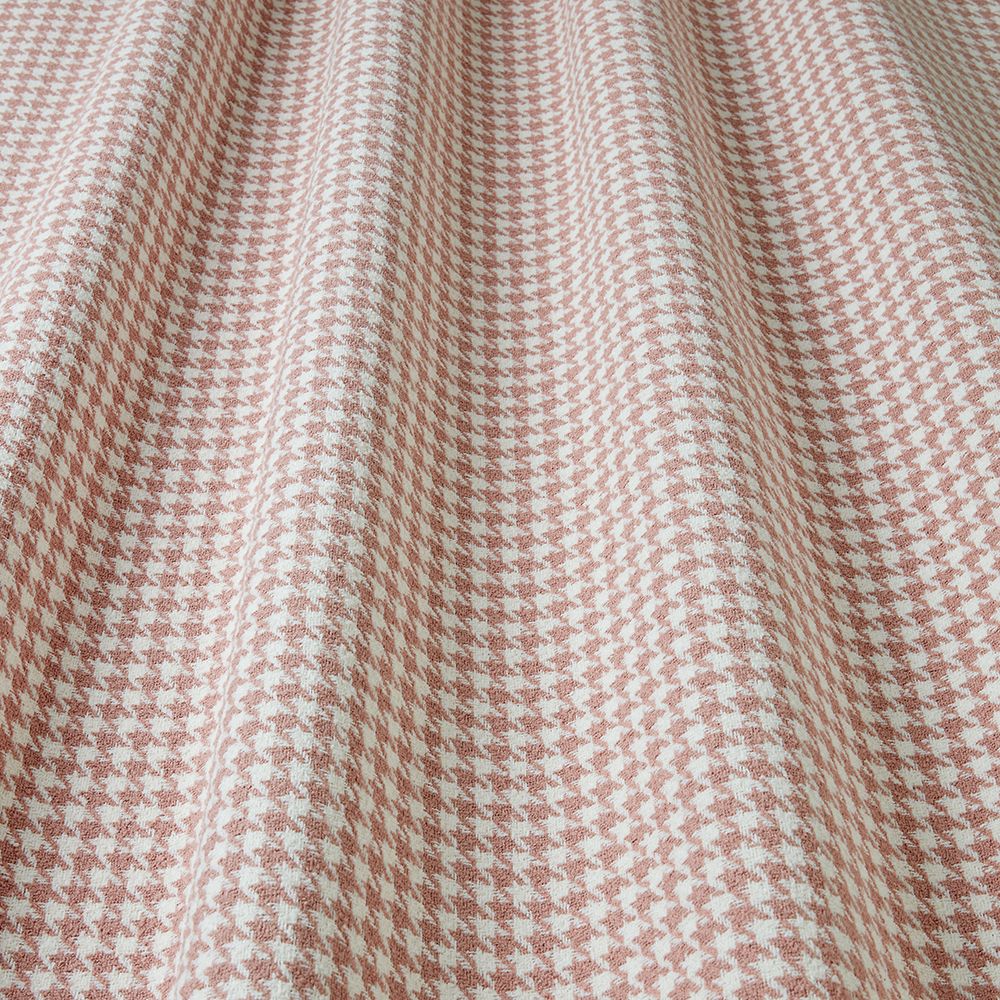 Close-up of a houndstooth patterned fabric with a pink and white colour scheme.