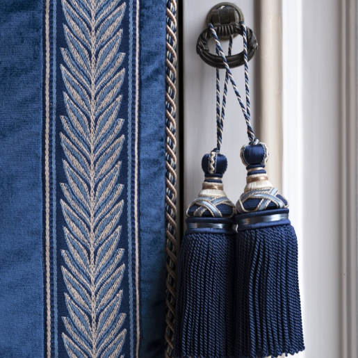 Close-up of a blue curtain with decorative tassels on a white background