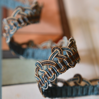 Close-up of a braided leather belt with blue accents on a blurred background