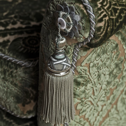 Decorative tassel with floral elements on a textured green fabric background