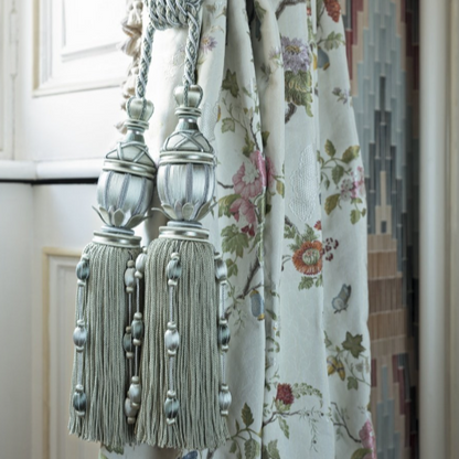 Decorative tassels on a floral curtain with a blurred background