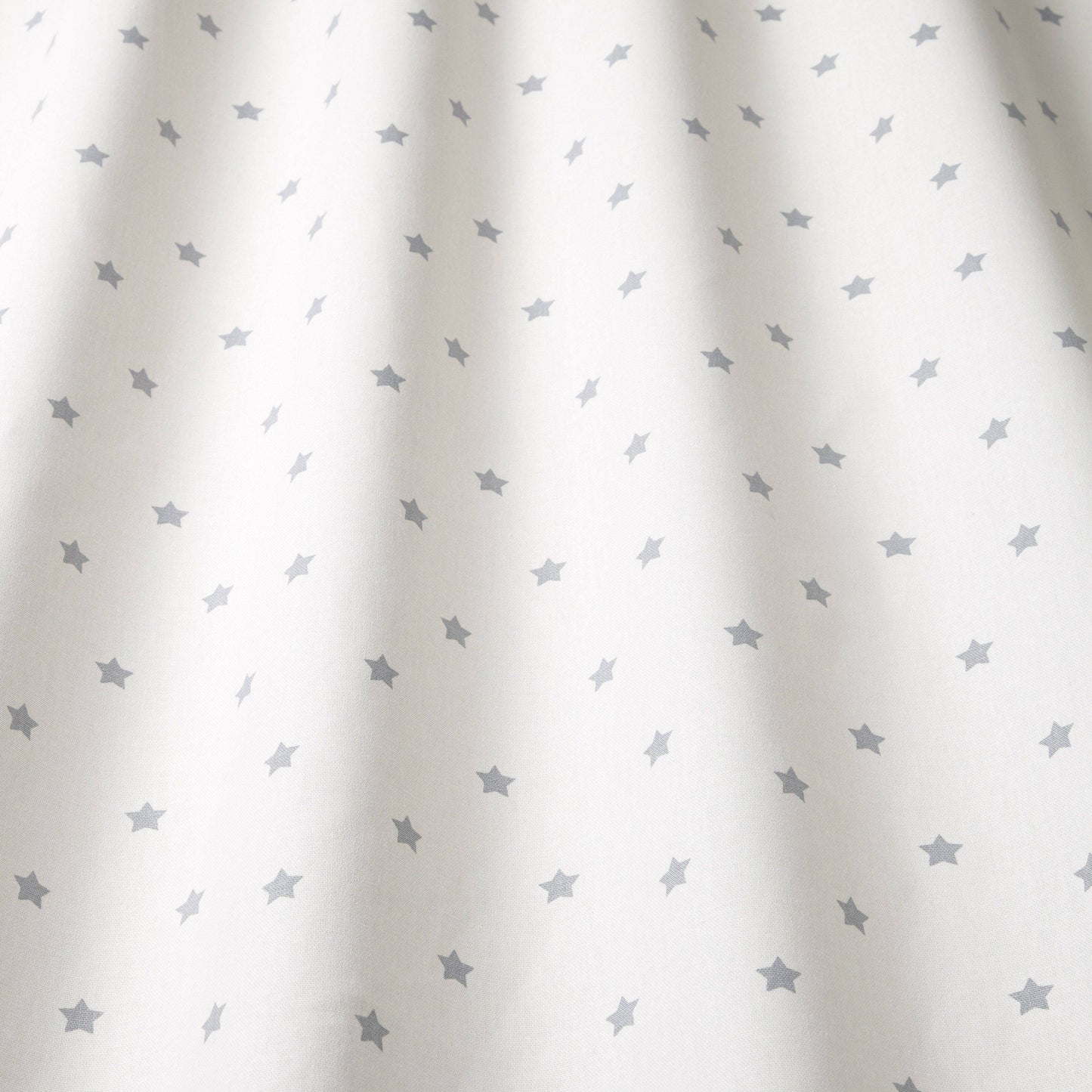 Close-up of Stardust Grey cotton fabric showing soft drape and grey star pattern, perfect for kids' room curtains and creative textile projects.