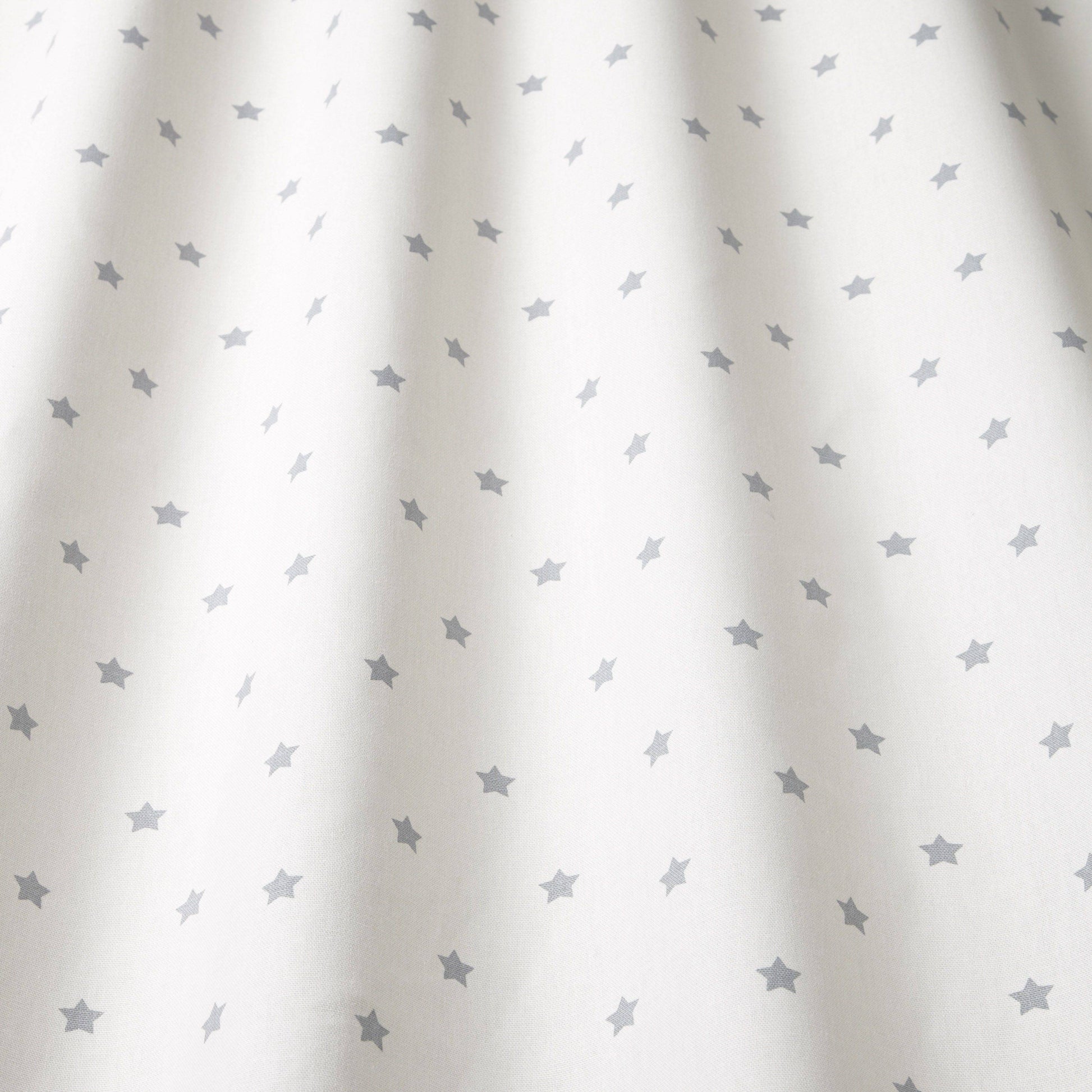 Close-up of Stardust Grey cotton fabric showing soft drape and grey star pattern, perfect for kids' room curtains and creative textile projects.