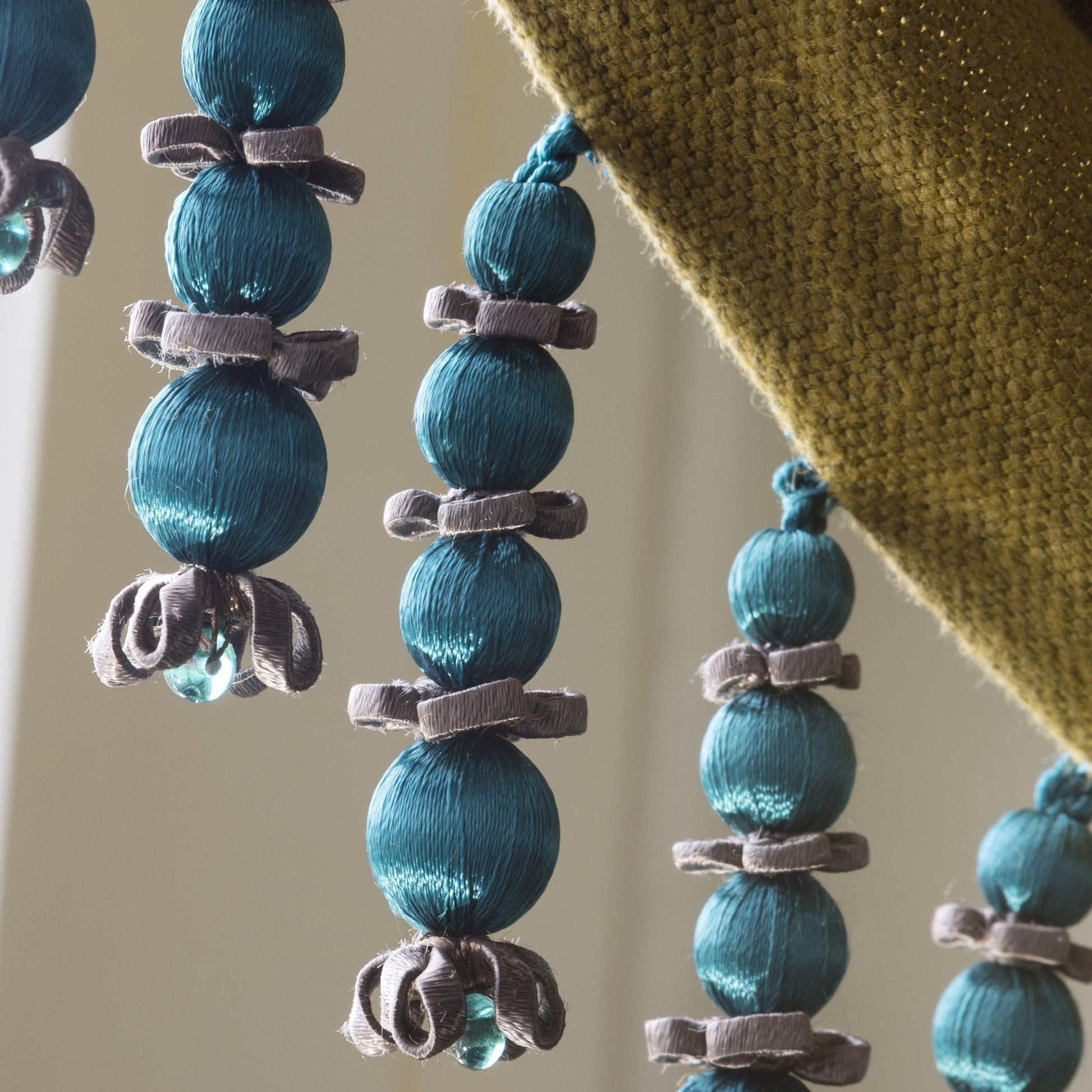 Close up of Valenza Beaded Drop Fringe in Verdigris Royale attached to a curtain 