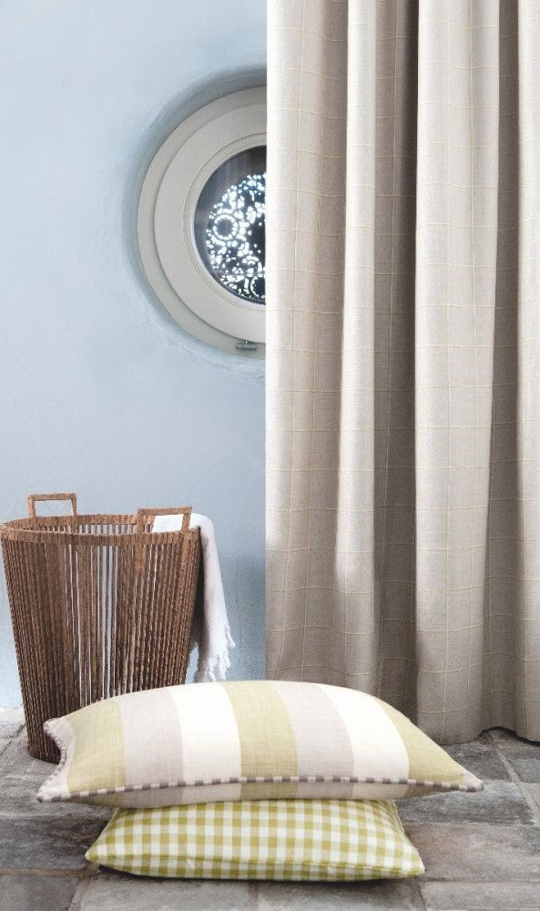 Decorative pillows featuring Beechwood Moss gingham fabric and striped linen, styled with neutral curtains and a wicker basket.